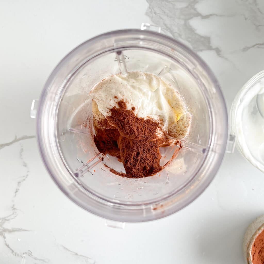 Adding Greek yogurt and cocoa powder to frozen bananas for creaminess, taste, and protein