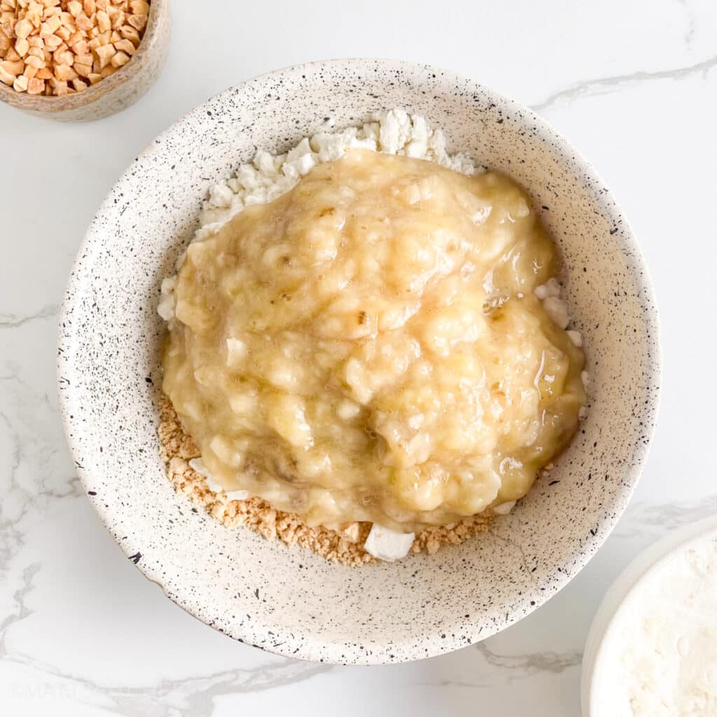 Mashed banana added to PB2 and protein powder in a bowl