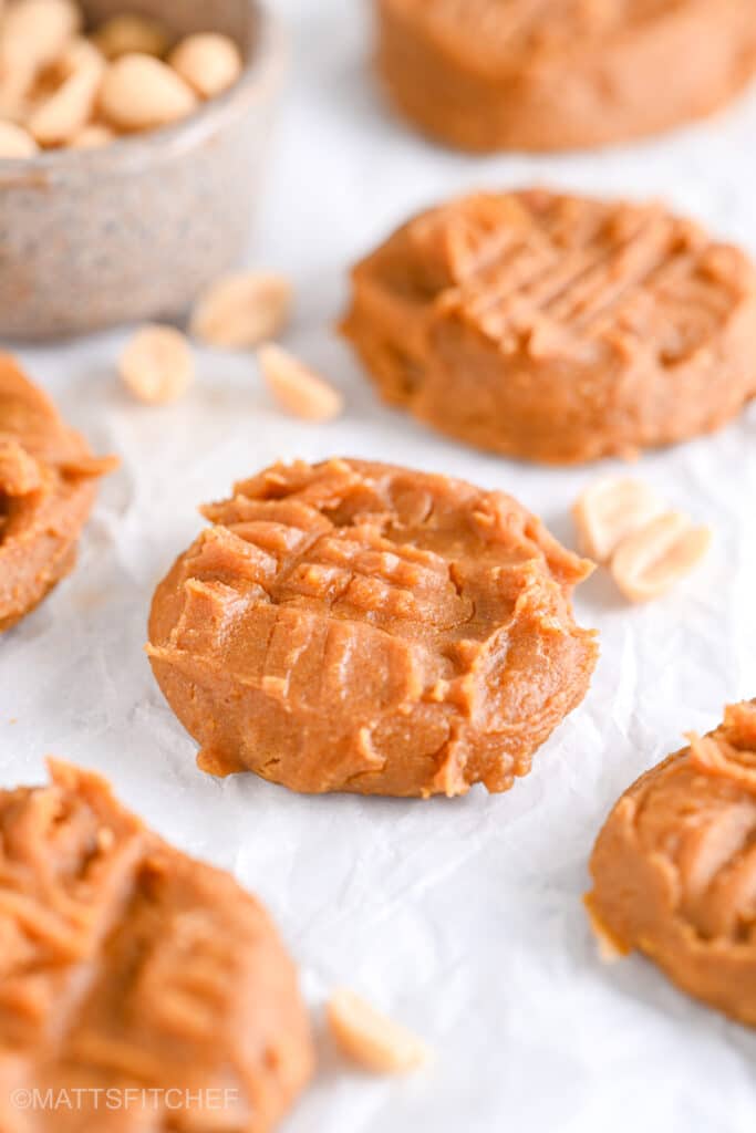 Front view of powdered peanut butter cookies, with peanuts in background