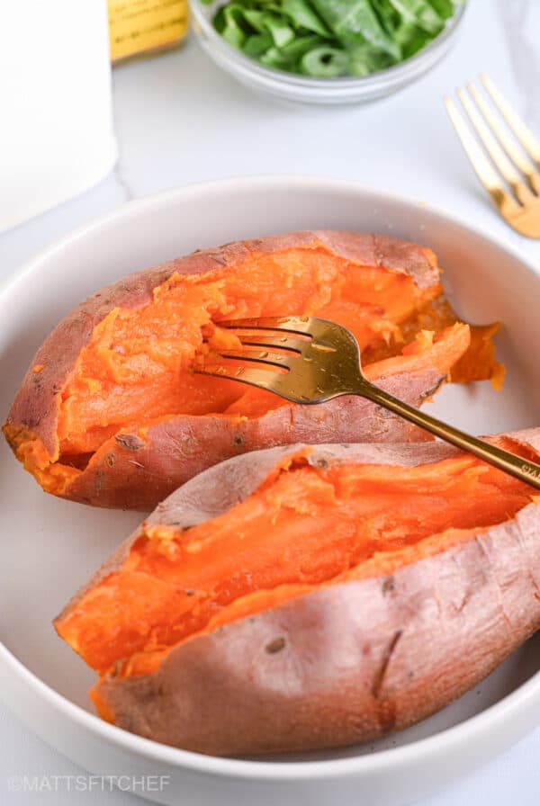 Poking steamed sweet potato with a golden fork, featuring a creamy, buttery, and fluffy flesh