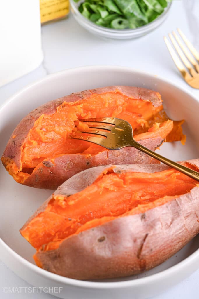 Poking steamed sweet potato with a golden fork, featuring a creamy, buttery, and fluffy flesh