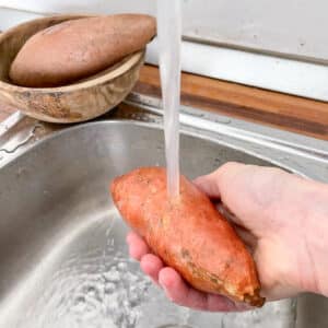 Washing medium sweet potato under cool running water before steaming
