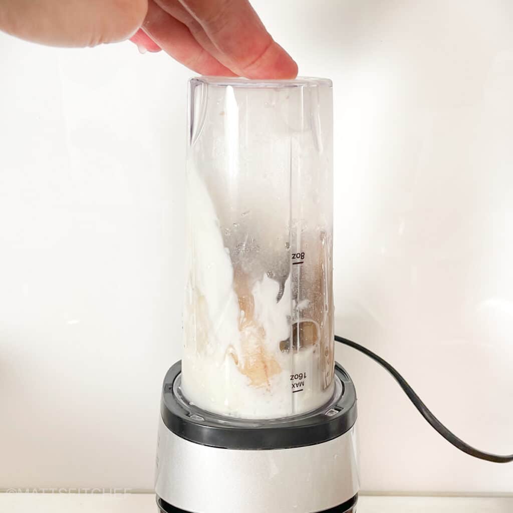 Banana, Greek yogurt, protein powder, milk and vanilla extract in a blender ready for blending