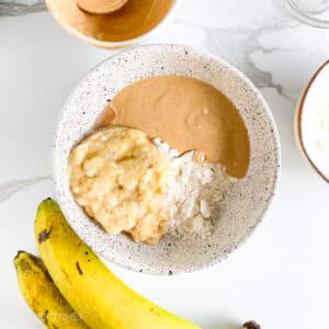 Protein powder, mashed banana and peanut butter in a bowl, ready to mix into a dough