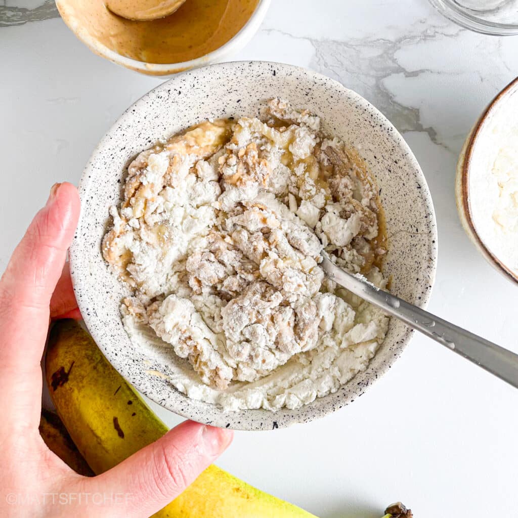 Mixing protein powder with banana and peanut butter for energy bites