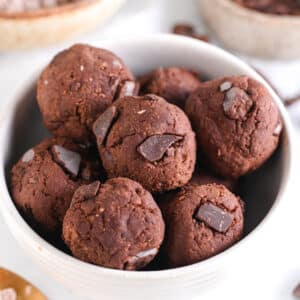Close-up of protein brownie bites with chocolate protein powder and chocolate chunks in the background