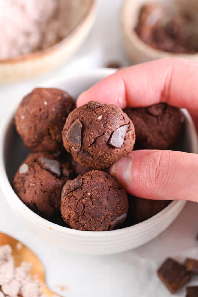 Chocolate protein ball being held between two fingers, ready to enjoy as a macro-friendly snack or post workout