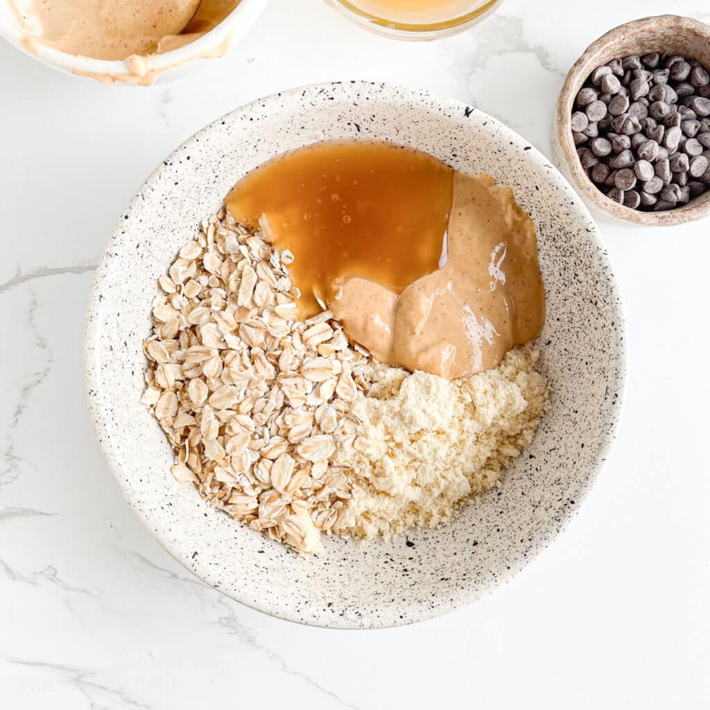 Peanut butter, protein powder, rolled oats and maple syrup in a bowl