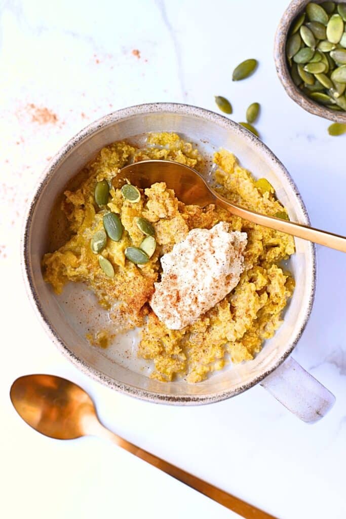 Creamy pumpkin oatmeal recipe topped with high protein cottage cheese and roasted pumpkin seeds