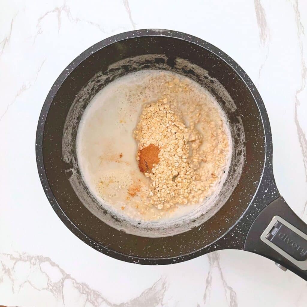 Rolled oats and pumpkin spice mix added to simmering milk