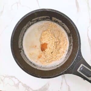 Rolled oats and pumpkin spice mix added to simmering milk