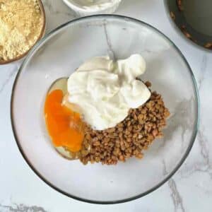 Cooked lentils, egg, Greek yogurt, baking powder and seasonings in a bowl ready for blending