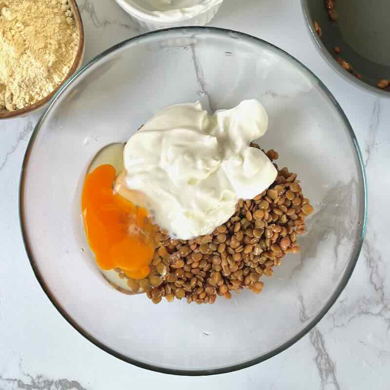 Cooked lentils, egg, Greek yogurt, baking powder and seasonings in a bowl ready for blending