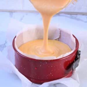 Pouring cottage cheese sweet potato cream into springform pan for baking